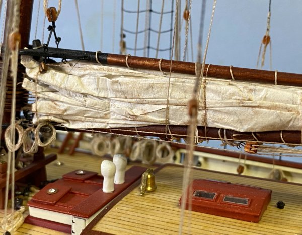 Furled main sail, coiled ropes, boom rigging